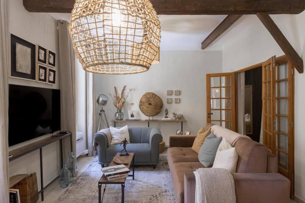 ein Wohnzimmer mit einem Sofa und einem Kronleuchter in der Unterkunft L'americannes - 2 Pièces Suquet in Cannes