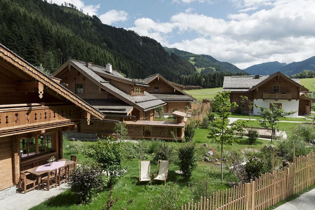 un grupo de edificios de madera en un campo con montañas en Feriendorf Holzlebn en Grossarl