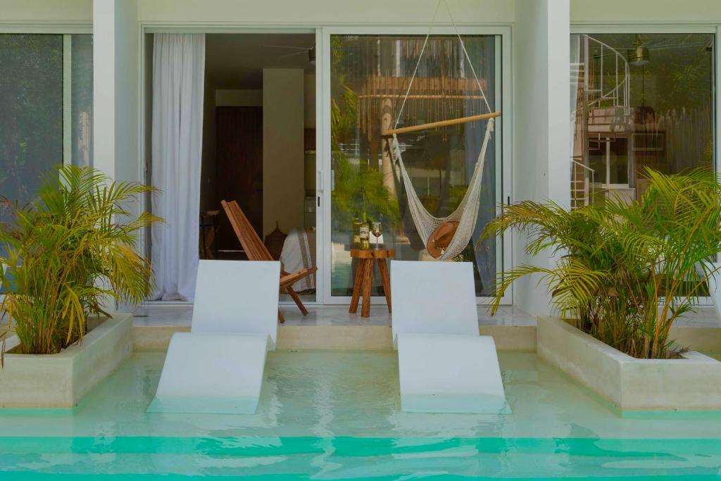 ein Haus mit einem Pool mit Stühlen und einer Hängematte in der Unterkunft Beautiful Swim-Up Apartment with Private Terrace & Hammoc, Pool & Gym in Tulum