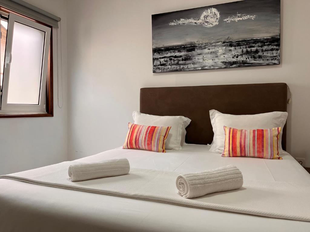 a large white bed with two pillows on it at Casa da Vila Guest House in Póvoa de Varzim