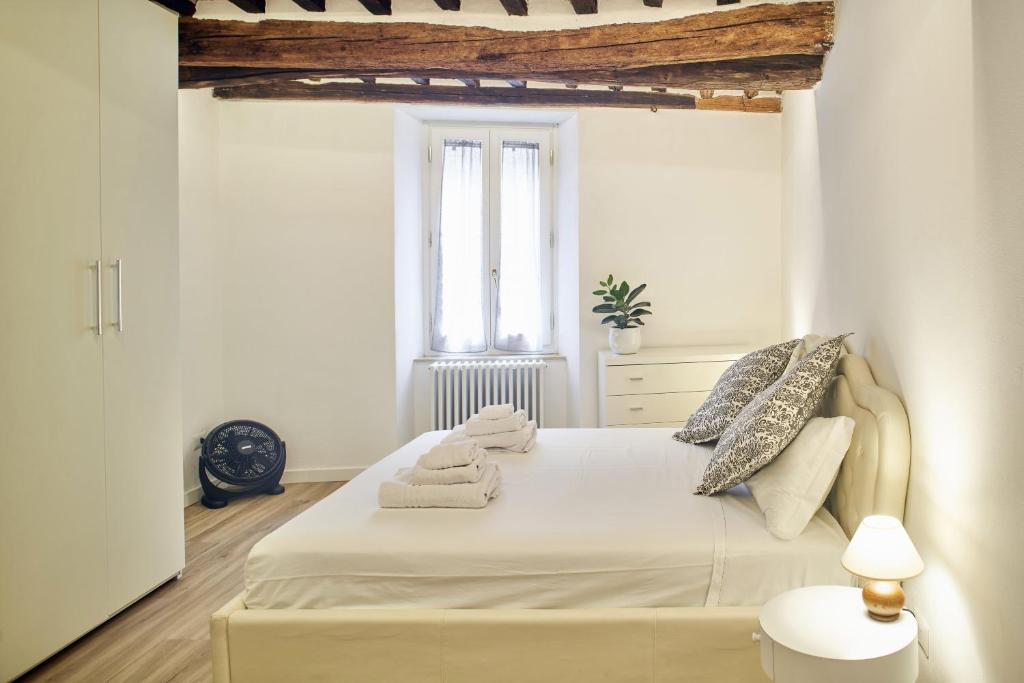 Un dormitorio con una cama blanca con toallas. en Casa Monelli, en Siena