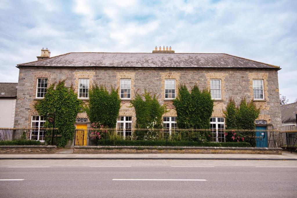 a large brick building with a fence in front of a street at Preston House in Abbeyleix