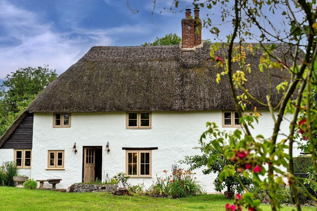 a large white house with a thatched roof at Finest Retreats - Manor Cottage in Winterborne Stickland