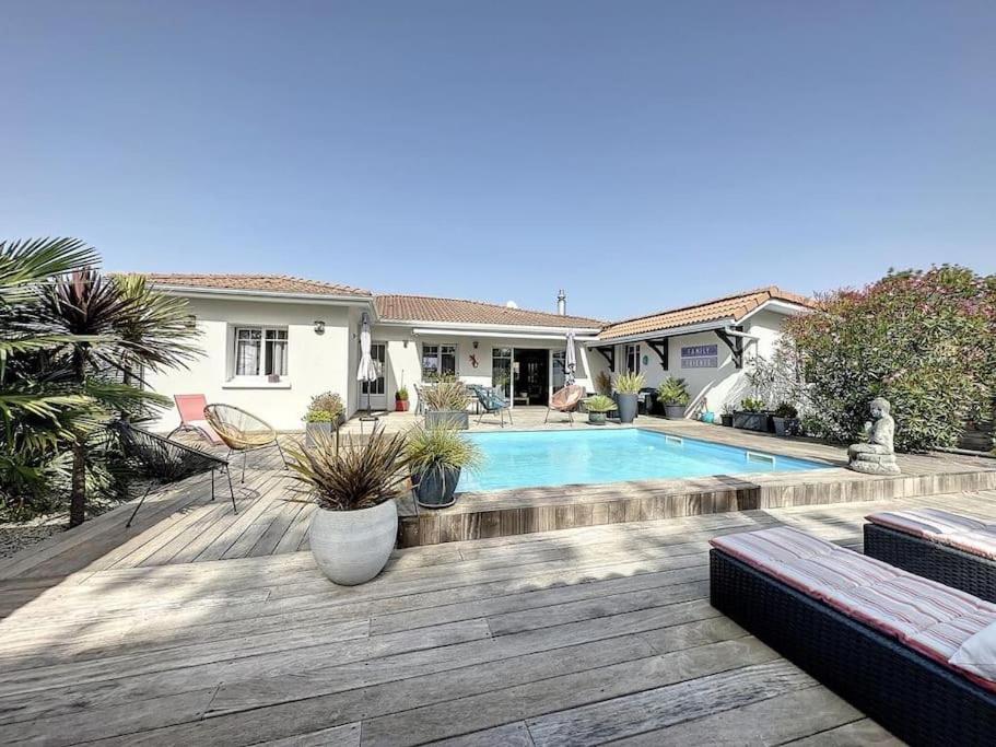 a backyard with a swimming pool and a house at Villa Nolaene, 8-9 pers, Piscine, Calme et Moderne in Gujan-Mestras