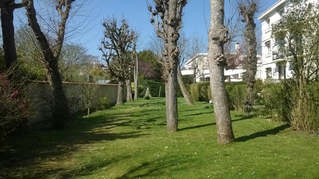 a yard with trees in the grass with a house at Chatou Centre Ville in Chatou