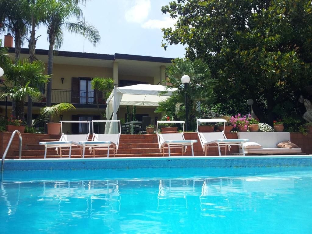 uma piscina com cadeiras e uma casa em Villa Carmen on Etna em Trecastagni