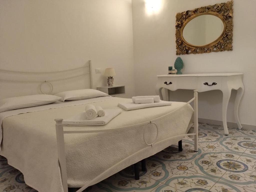 Habitación blanca con cama y espejo en Dimora d'Estate (Sicilian Holidays), en Milazzo