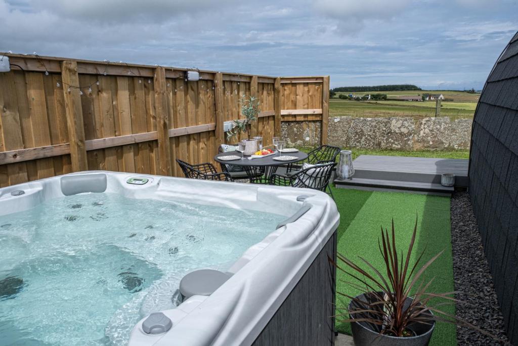 a hot tub in a backyard with a table and chairs at Glengolly Getaways in Thurso