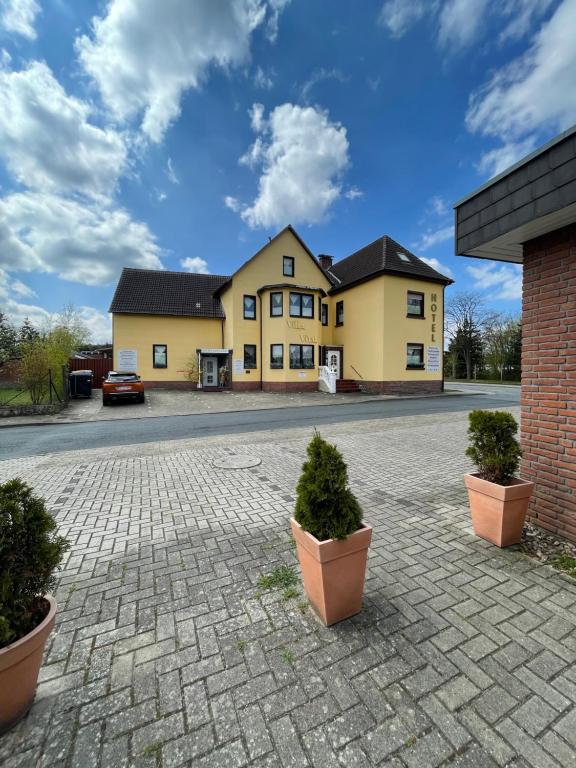 ein Haus mit zwei Topfpflanzen davor in der Unterkunft Hotel Villa Vital Munster in Munster im Heidekreis