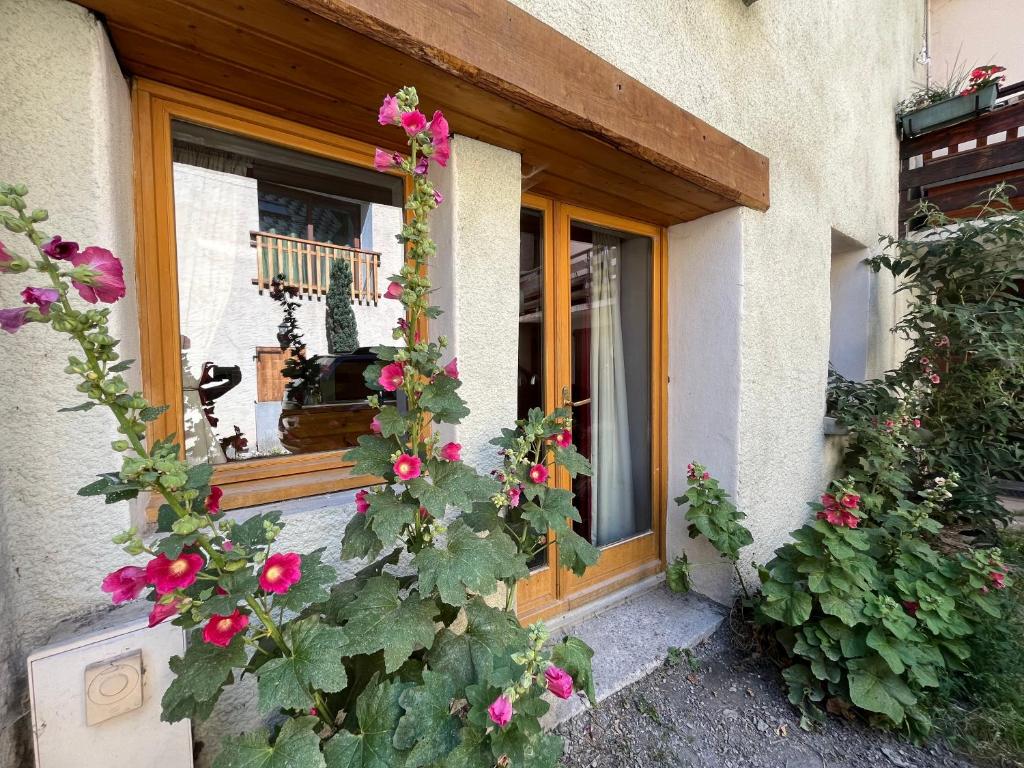 une fenêtre d'une maison ornée de fleurs roses dans l'établissement The Stable House Bourg d’Oisans -bike/hike/ski, au Bourg-dʼOisans