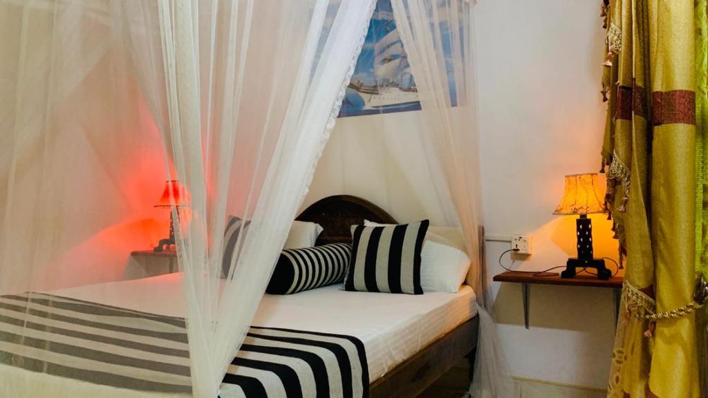 1 dormitorio con 1 cama con cortinas y lámparas en Sisira Natural Lodge - Sigiriya, en Sigiriya