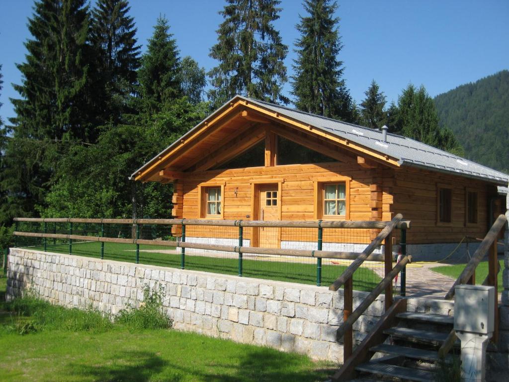 drewniany domek z kamienną ścianą przed nim w obiekcie Chalet Camping Faè 2 w Madonna di Campiglio