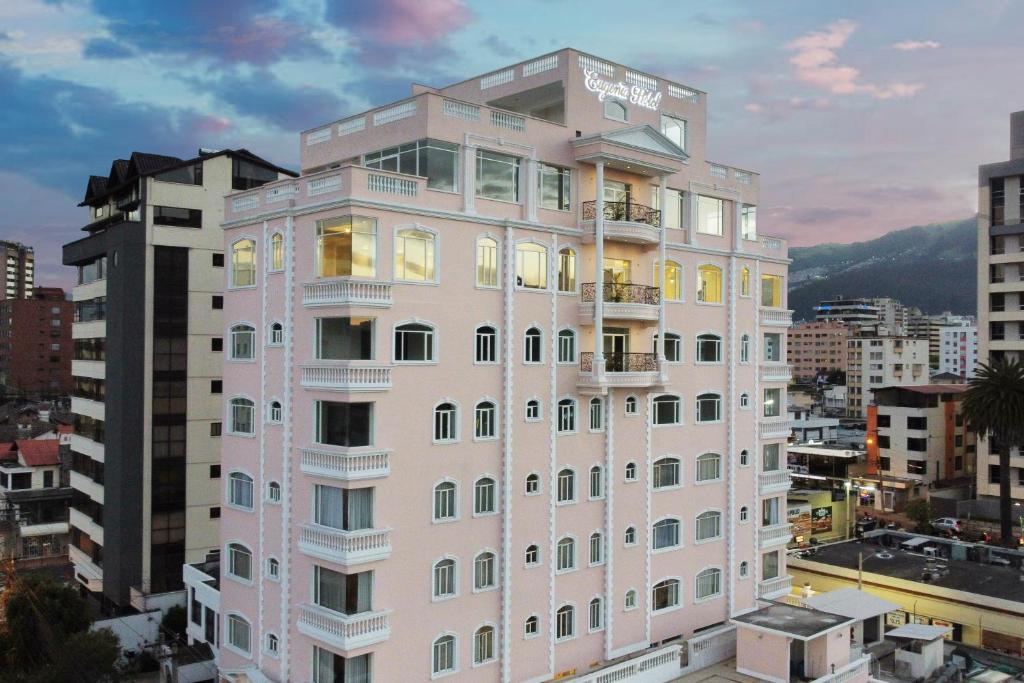 un edificio alto de color rosa con ventanas en una ciudad en Eugenia Hotel en Quito