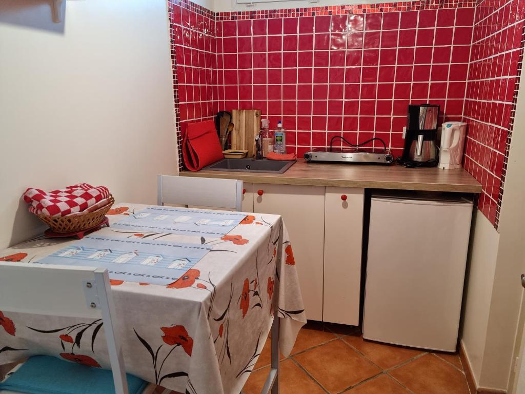 cocina con mesa y pared de baldosas rojas en Joli studio St André Les Alpes confortable et bien situé, idéal randonnées, parapente en Saint-André-les-Alpes