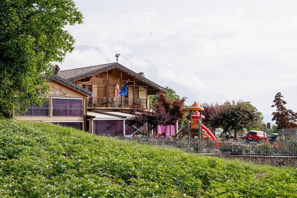 una casa en una colina con un parque infantil en Agritur Maso alle Rose B&B e Restaurant, en Fiavè