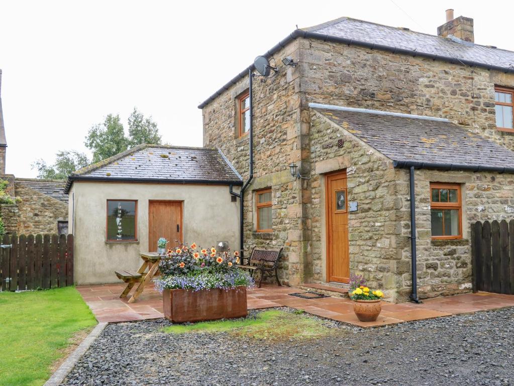 an old stone house with a patio with flowers at The Barn Cottage in Slaley