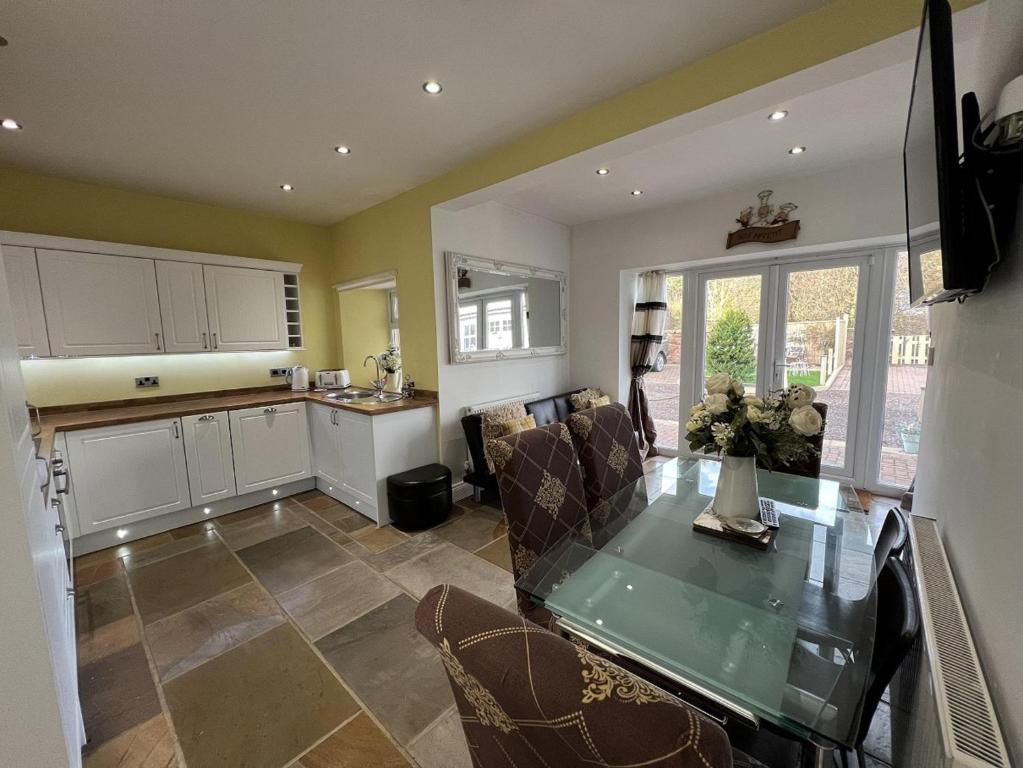 een keuken en een woonkamer met een glazen tafel en stoelen bij 3 Bedrooms 2 Bath Cottage Balcony Garden Dogs Free in Berwick-Upon-Tweed