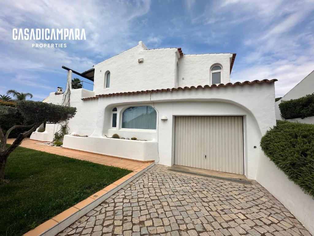 a white house with a garage on a driveway at Casa di Campara Villa Faro in Faro