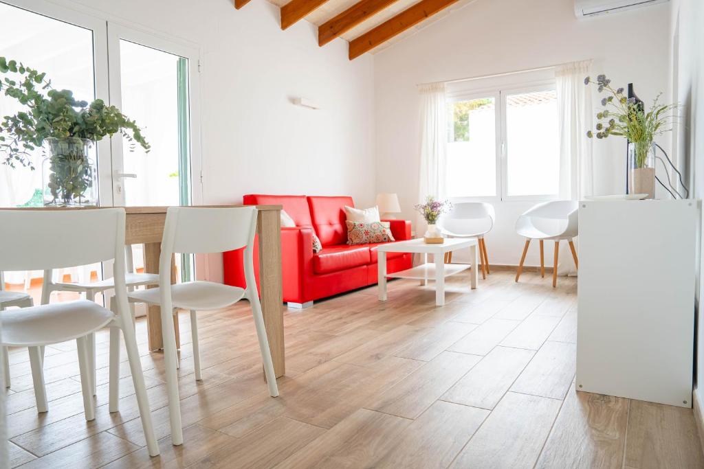 a living room with a red couch and white chairs at Apartamento Calan Bosch, Ciutadella in Cala'n Bosch