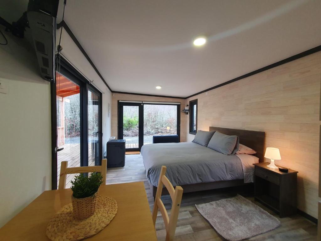 a bedroom with a bed and a table and some windows at Tiny House Suite Los Mallines de Malalcahuello in Malalcahuello
