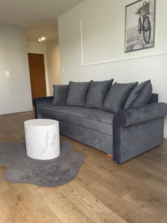 a living room with a blue couch and a table at Apartament Tęczowa in Gdynia