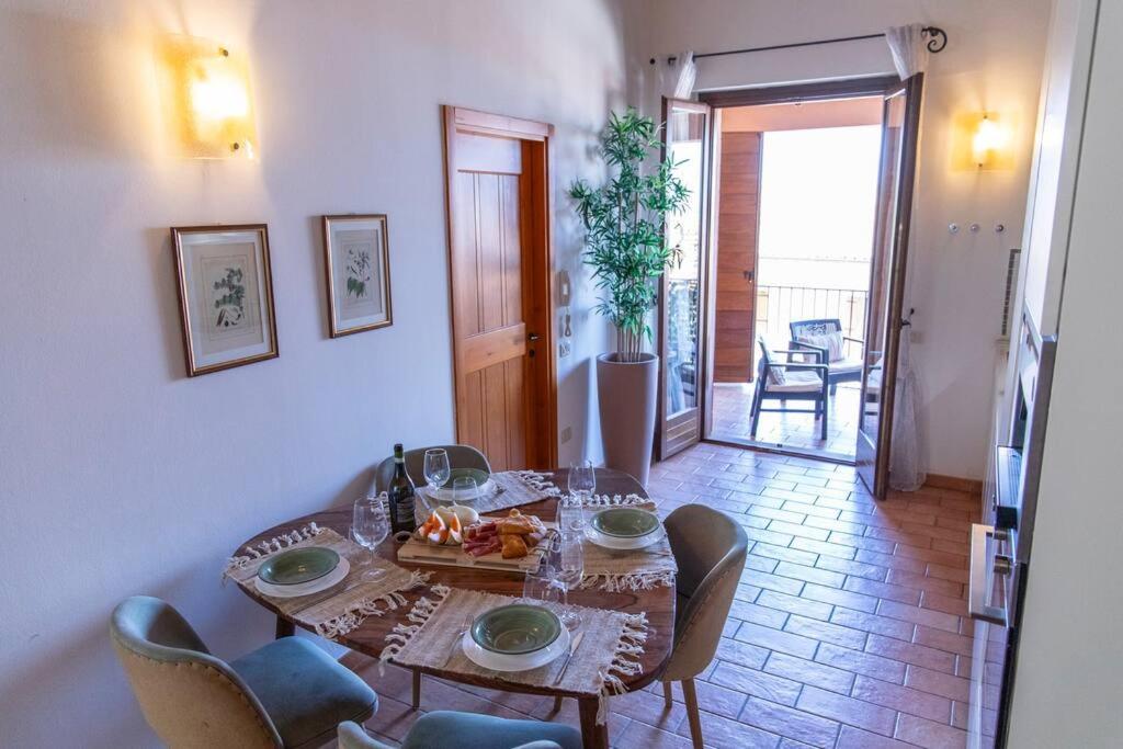 un comedor con mesa y sillas y una habitación con puerta en Anemoni Home nel Borgo di Montegridolfo by Yohome, en Montegridolfo