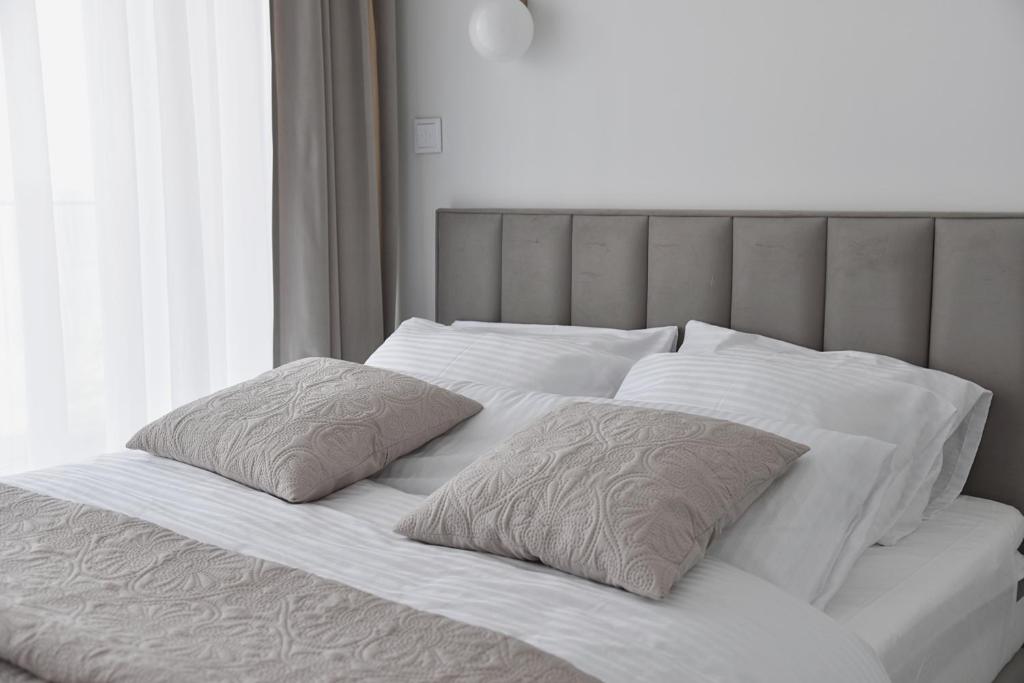 Una cama blanca con dos almohadas encima. en Rewal HEVENIA Premium Baltic Apartment with SPA access, en Rewal