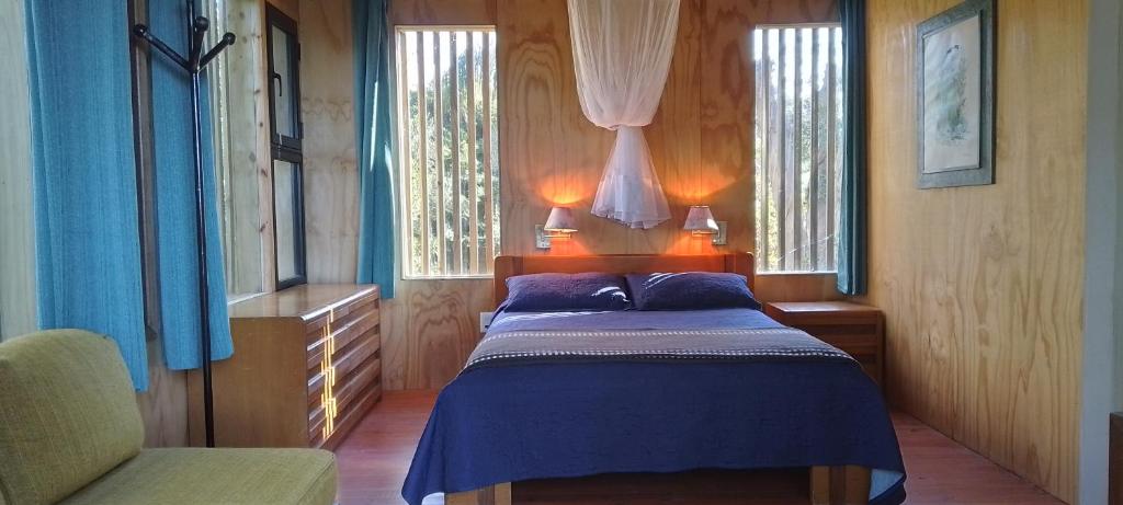 a bedroom with a blue bed with two windows at Posada IRSIS in La Pedrera