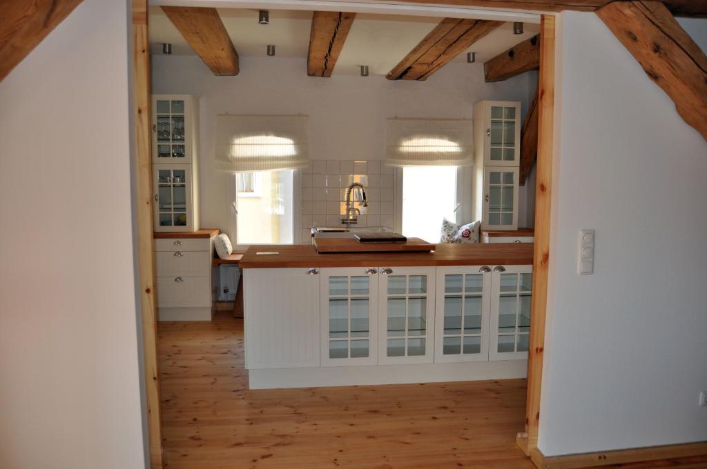 a kitchen with white cabinets and a wooden floor at Der Speicher in Wolgast