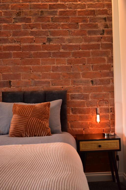 a bedroom with a brick wall with a bed and a lamp at Entire house in Retford city centre in Retford