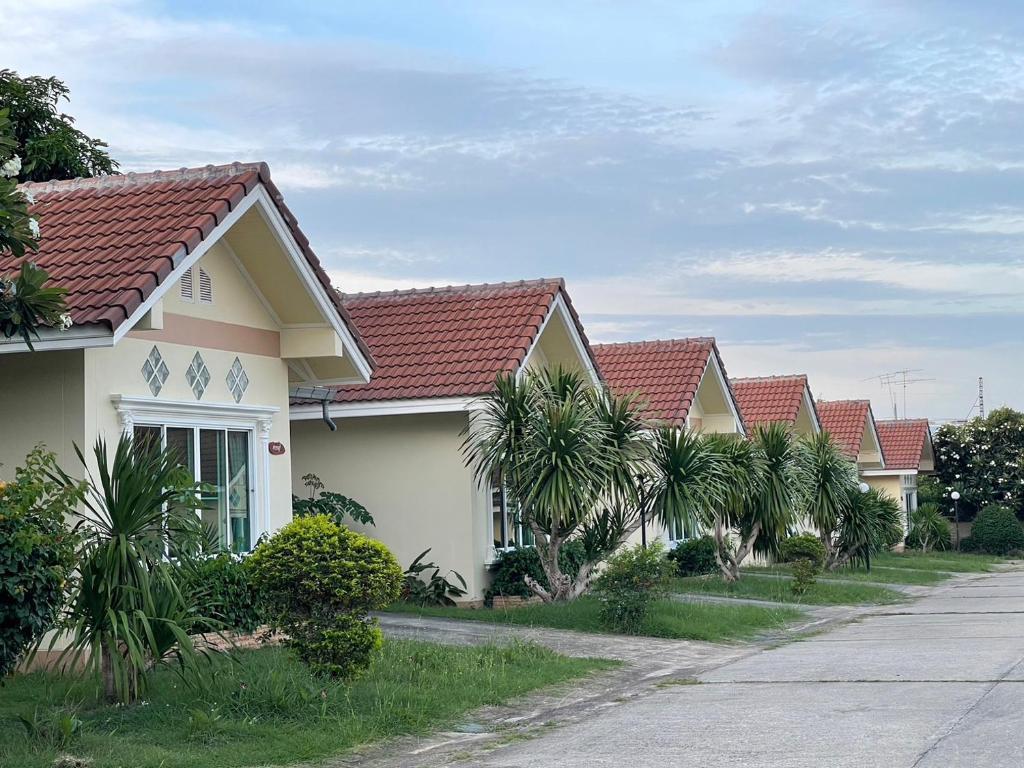 eine Reihe von Häusern mit Palmen neben einer Straße in der Unterkunft ธนวรรณรีสอร์ท - Thanawan Resort in Ban Phra Trong