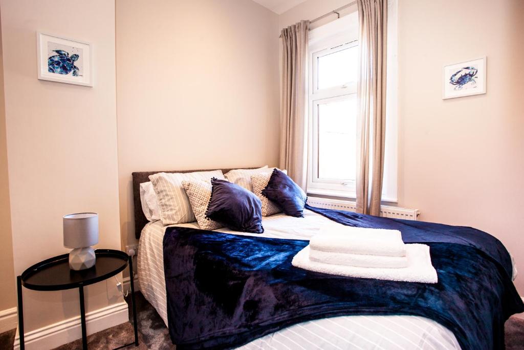 a bedroom with a bed with a blue blanket and a window at Contractor house, sleeps 7, close to restaurant's & bars, long stays available, Oveyo Accommodation in Middlesbrough