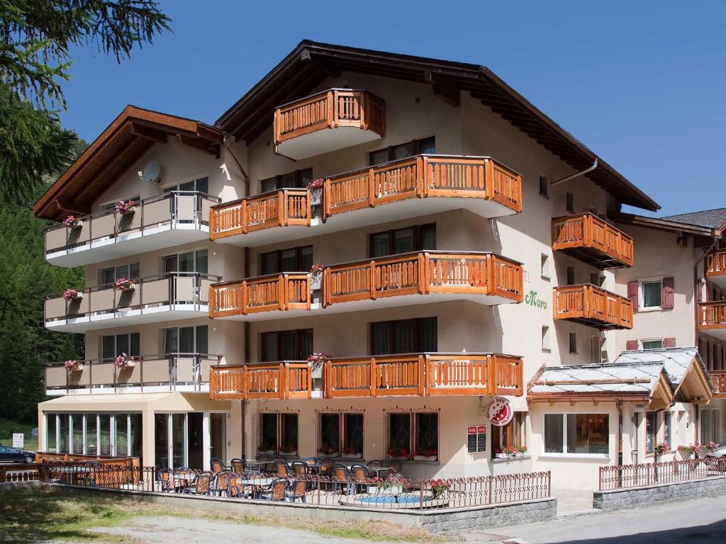 a large building with wooden balconies and tables at Hotel Monte-Moro in Saas-Almagell
