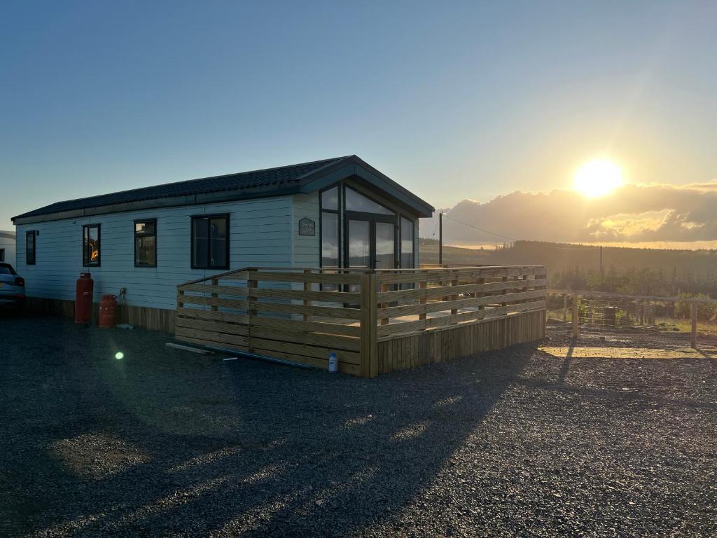 a small house with a sun in the background at Maneight Luxury Lodge with hot tub in New Cumnock