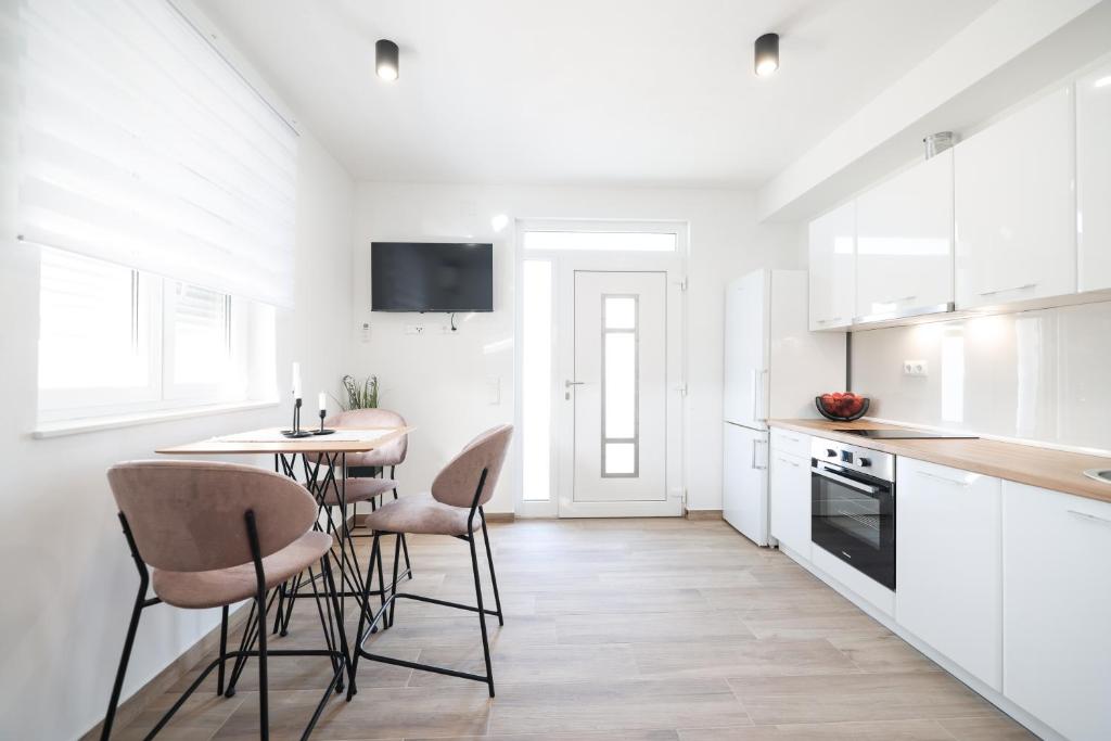 cocina con armarios blancos, mesa y sillas en New Family Apartments with private parking near Zadar en Murvica