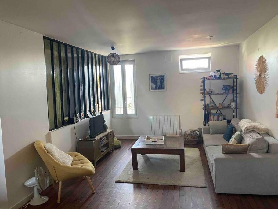 ein Wohnzimmer mit einem Sofa und einem Tisch in der Unterkunft Appartement chaleureux au cœur de la ville in Saintes