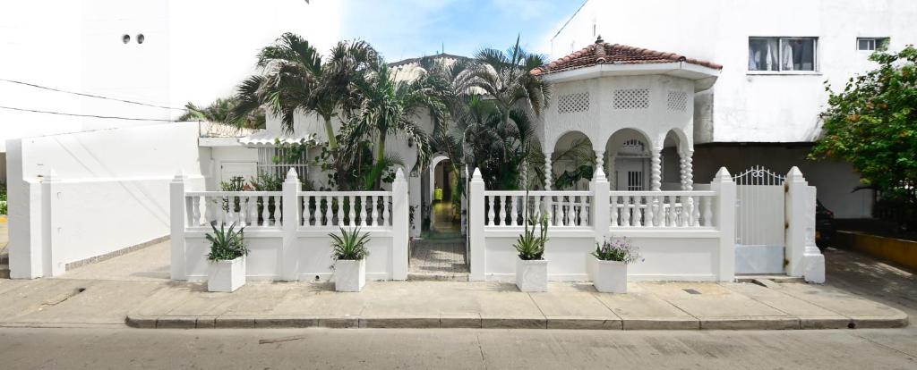 uma cerca branca em frente a uma casa com vasos de plantas em Casa Hotel Terraza del Cabrero em Cartagena de Indias
