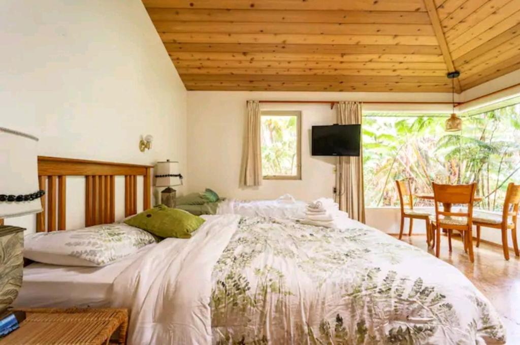 a bedroom with a large bed and a table and chairs at Kilauea iki- Hale Kumu La'au in Volcano