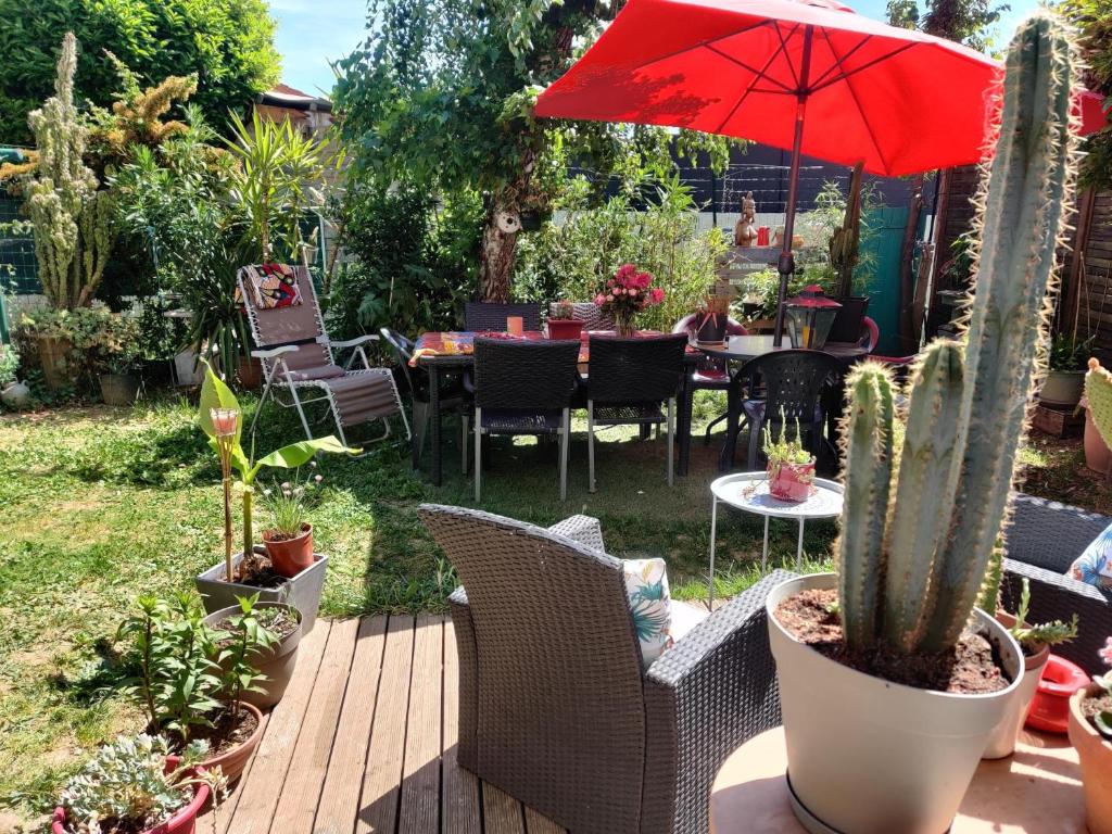 un patio con mesas, sillas y una sombrilla roja en La Villa Bleue, en Beauchastel