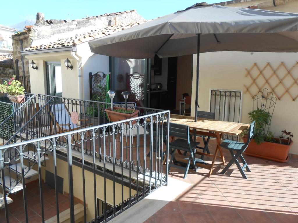 a patio with a wooden table and an umbrella at Appartamenti Lascaris in Lascari