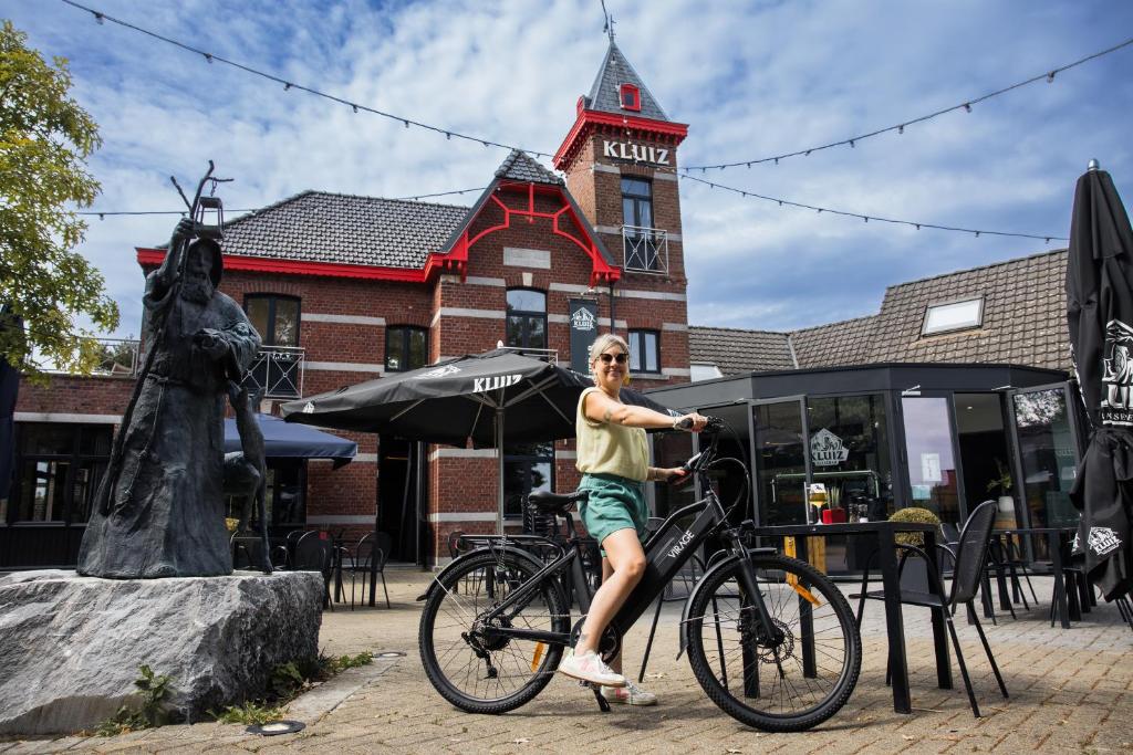 un hombre montando una bicicleta delante de un edificio en Appartement du Mont de L’Enclus, en Buisestraat