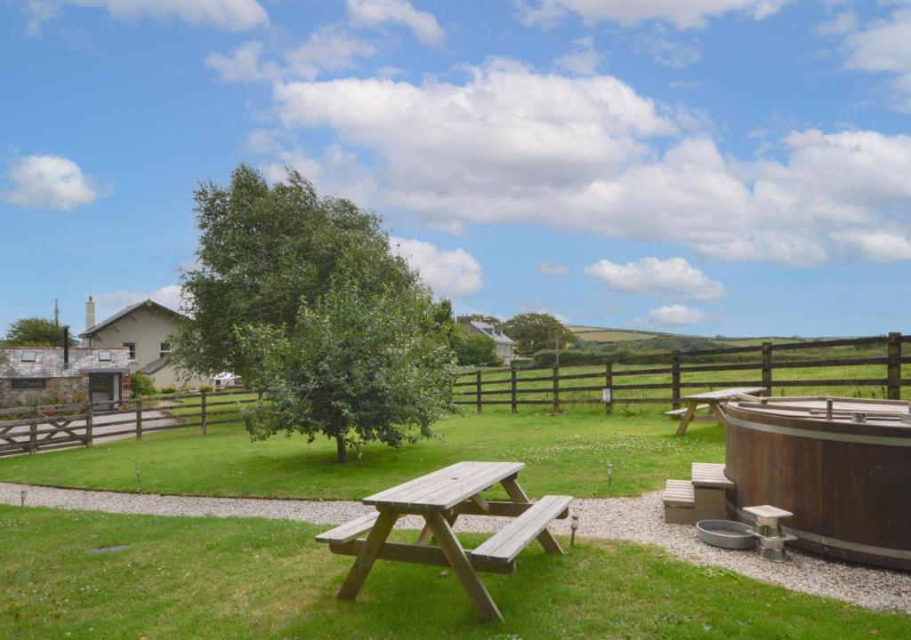 a picnic table and a hot tub in a field at Higher Treliver Farmhouse in Saint Wenn