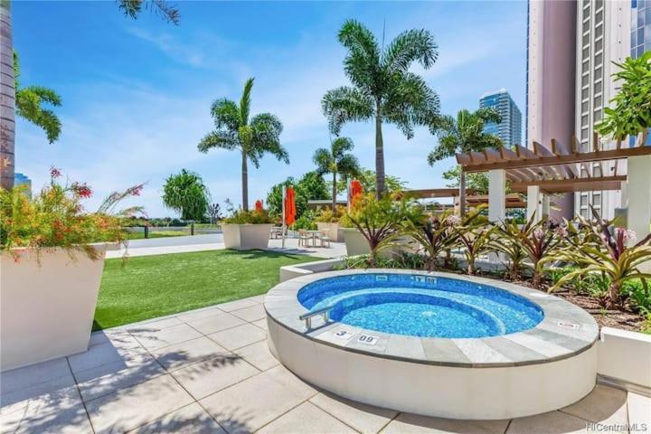 a swimming pool in a garden with palm trees at Luxury Residence at Kakaako in Honolulu