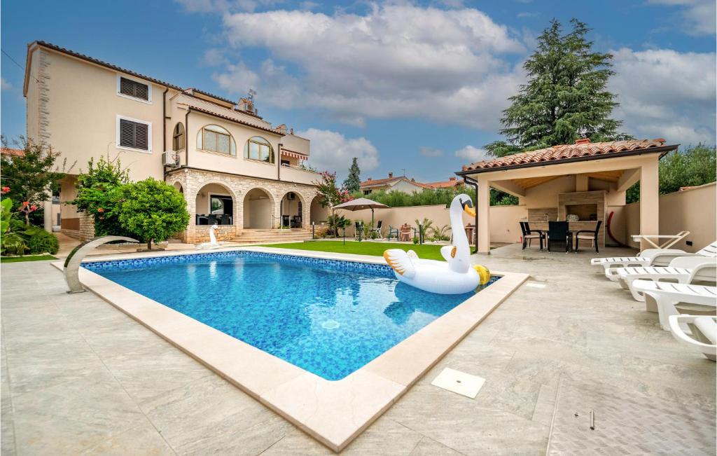 a swimming pool with a swan in front of a house at 2 Bedroom Lovely Apartment In Medulin in Medulin