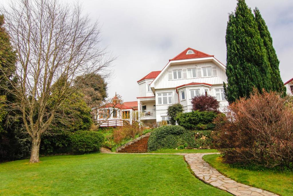 ein großes weißes Haus mit Rasen und Bäumen in der Unterkunft Hotel Costanera - Caja Los Andes in Valdivia