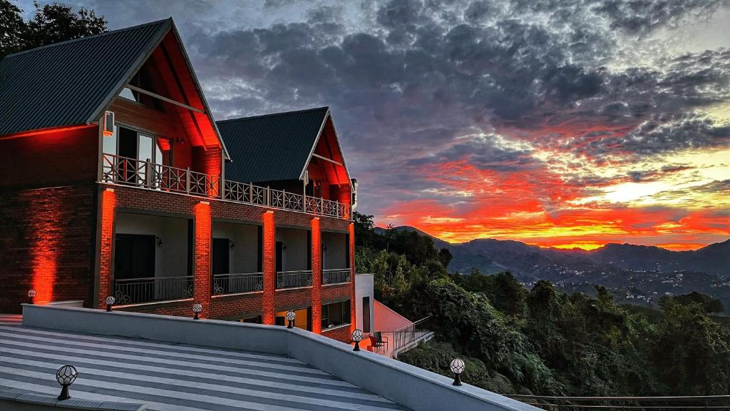 a building with a sunset in the background at Moon House Bungalow in Rize