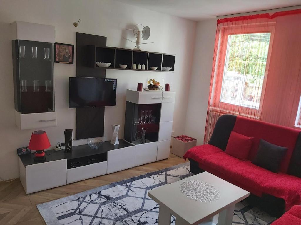 uma sala de estar com um sofá vermelho e uma televisão de ecrã plano em Stan na dan Vasilije em Zvornik