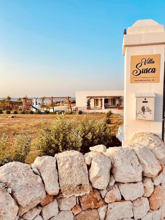 a stone wall in front of a sign and a building at Villa Susca - villa sul mare in Monopoli