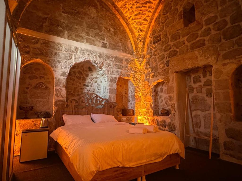 um quarto com uma cama numa parede de pedra em Paşaoğlu Konağı & Boutique hotel em Mardin