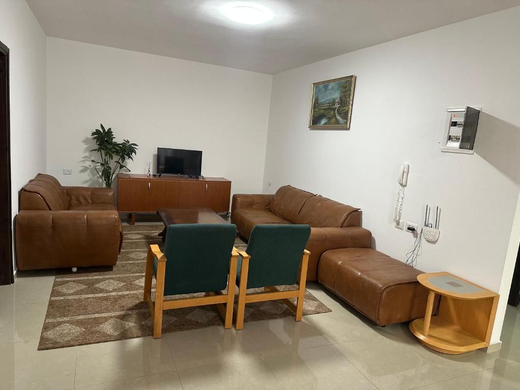 a living room with a brown leather couch and chairs at Ghanem building 15 in Bethlehem